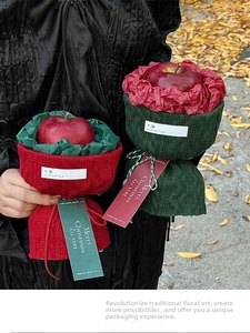 Close-up of red and green knitted Christmas apple gift packaging with festive tags