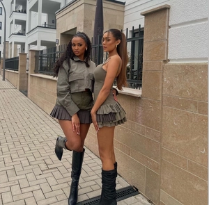 Detail of army green pleated mini dress and jacket with black leather boots outdoors