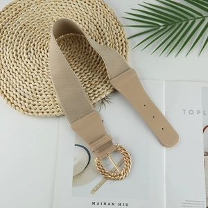 Dettaglio della cintura elastica beige con fibbia rotonda dorata a trama a spirale