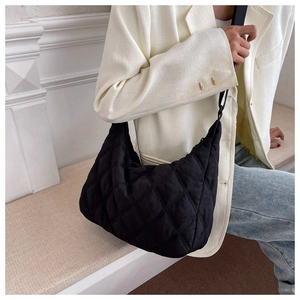 Detailed view of black quilted nylon half-moon shoulder bag styled with casual outfit