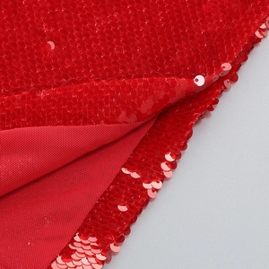 Close-up of red sequin fabric texture with reflective patterns on the long sleeve dress