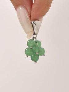 Detailed view of emerald green cluster bead pendant with polished silver clasp held by hand