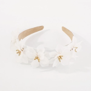 Détail de fleurs en tissu blanc avec pistils dorés sur un serre-tête beige de style rétro