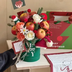 Christmas gift bucket with red apples, roses and pine branches in a green Merry bucket