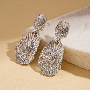 Boucles d'oreilles géométriques argentées texture coquillage sur socle en marbre