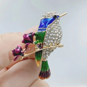 Close-up of hummingbird brooch featuring colorful enamel wings and crystal rhinestones