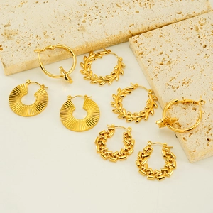 Detailed view of assorted 18K gold-plated chunky stainless steel hoop earrings on stone