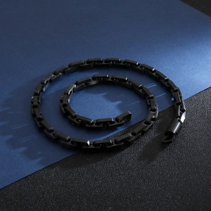 Macro shot of black punk interlocking metal chain necklace on a textured dark background