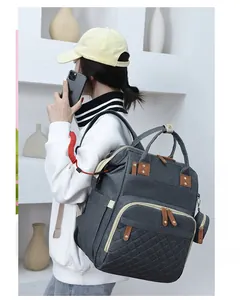 Rear view of model wearing dark grey quilted diaper backpack with brown leather accents