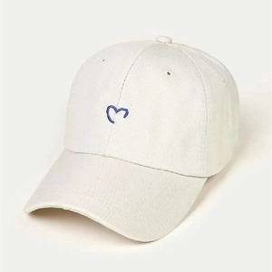 Close-up of blue heart embroidery on premium white cotton baseball cap with ventilation eyelets
