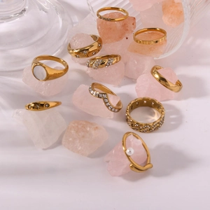 Close-up of assorted gold stackable rings with crystals and pearls on quartz stones