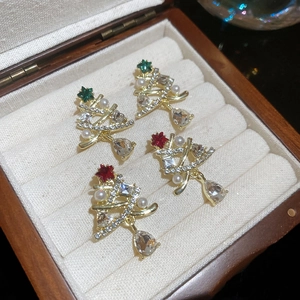 Detailed macro view of gold Christmas tree earrings with pearls and red green gemstones