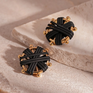 Macro detail of vintage woven faux leather compass earrings with golden metal frames