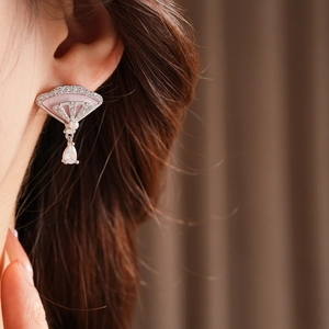Close-up of pink fan-shaped zircon earrings with drop pendant and pearls on model