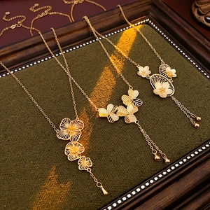 Detail shot of gold-plated flower necklaces with tassels on a dark wood display tray