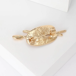Vintage gold painter palette brooch with crossed brushes on a white geometric background