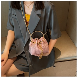 Close-up of pink rhinestone bucket bag with golden ring handle and elegant tassels