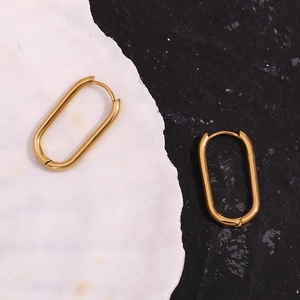 Detail of 18K gold-plated oval hoop earrings with a secure clasp on textured background