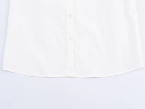Detailed view of white shirt hem with round cut and elegant pearl buttons