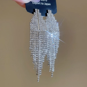Détail de glands argentés avec des strass brillants sur des boucles d'oreilles géométriques