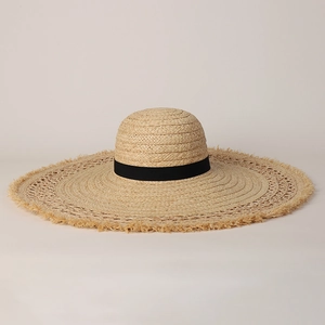 Detailed macro view of woven raffia sun hat with raw frayed edges and black ribbon