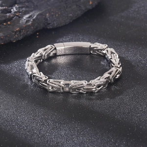 Detail of 8mm silver Byzantine steel chain bracelet on a black textured rock surface