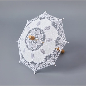 Top-down view of white floral lace bridal umbrella with natural wooden handle for weddings