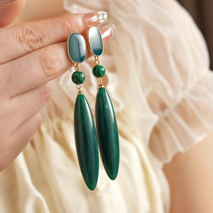 Close-up of vintage malachite drop earrings with green teardrop pendants on model