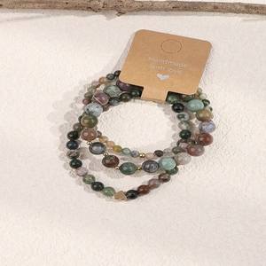 Close-up of three handmade natural stone beaded bracelets with a gold heart charm
