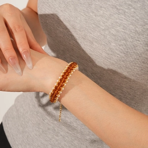 Detail of amber faceted beads and pearls on a gold-tone bracelet worn by a model