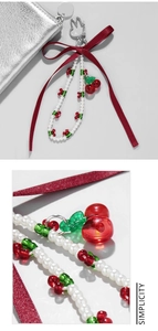 Detail of beaded phone strap with red cherry charms, pearls, and a silky red ribbon bow