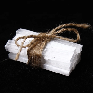 Natural selenite crystal wands bundled with jute rope against a black background