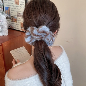 Dettaglio di un elastico per capelli a righe blu e marroni indossato su una coda
