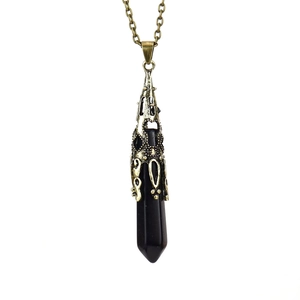 Detailed close-up of a hexagonal obsidian stone pendant with antique bronze filigree cap