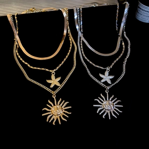 Detail of triple-layered necklaces with sun and starfish pendants in gold and silver