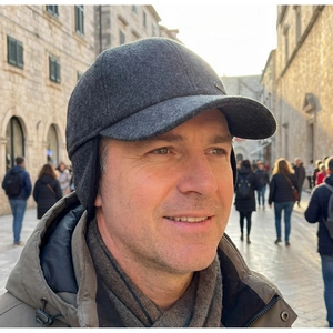 Close-up of dark grey wool winter cap with ear flaps and small metal logo detail