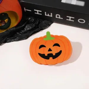 Detail of a bright orange pumpkin hair claw with a green stem and a black smiley face