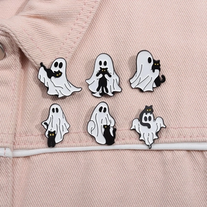 Set of 6 Halloween enamel pins with cute ghost and black cat designs on pink denim fabric