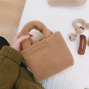 Gros plan d'un mini sac à main en laine d'agneau camel avec accessoires assortis sur tissu