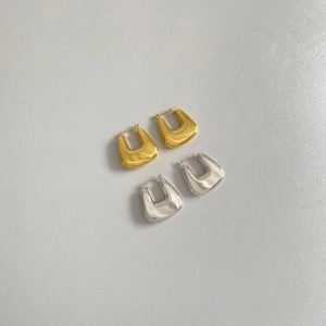 Close-up of geometric U-shaped hollow earrings in polished gold and silver finishes
