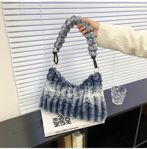 Detail of blue and white plush handbag featuring fuzzy ball handle and striped texture