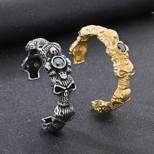 Detail of gothic skull bangles in silver and gold finish with black zircon stones