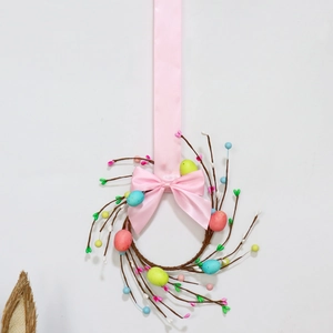 Detail view of Easter wreath with pastel eggs, small berries, and pink silk bow