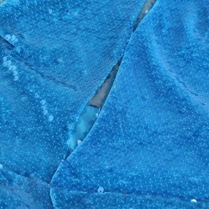 Macro shot of shimmering blue sequins and detailed stitching on the evening dress