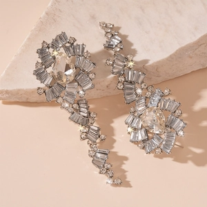 Macro detail of silver diamond earrings with water drop tassels on marble stone
