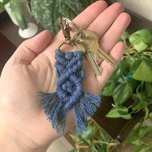 Blue macrame cotton cord keychain with bronze clasp shown in hand to highlight texture