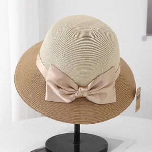 Elegant two-tone sun straw hat with a large satin bow on a professional display stand