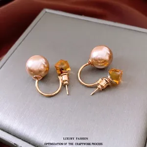 Boucles d'oreilles dorées avec perle champagne et cristal jaune en gros plan élégant