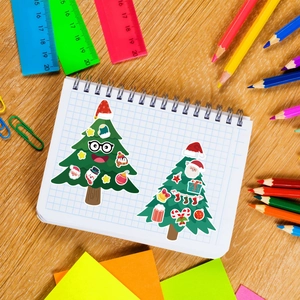 DIY Christmas tree stickers for kids featuring festive cartoon faces on grid paper