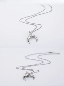 Detailed close-up of a silver polished crescent moon pendant on a delicate ball chain necklace